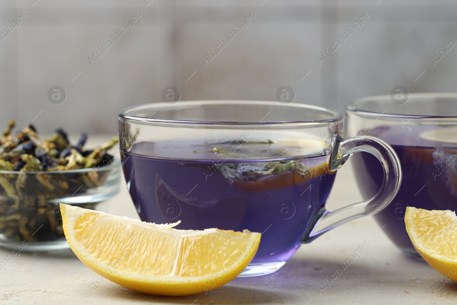 Photo of Delicious butterfly pea flower tea with lemon on gray textured table, closeup