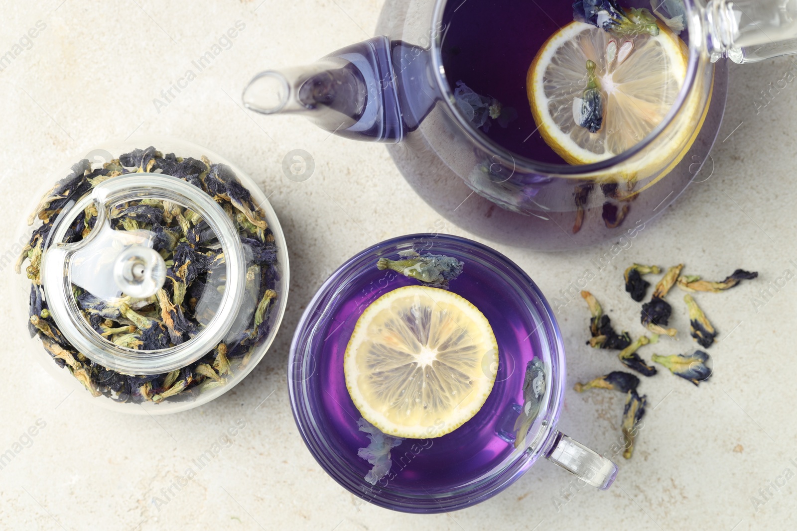 Photo of Delicious butterfly pea flower tea with lemon on gray textured table, flat lay