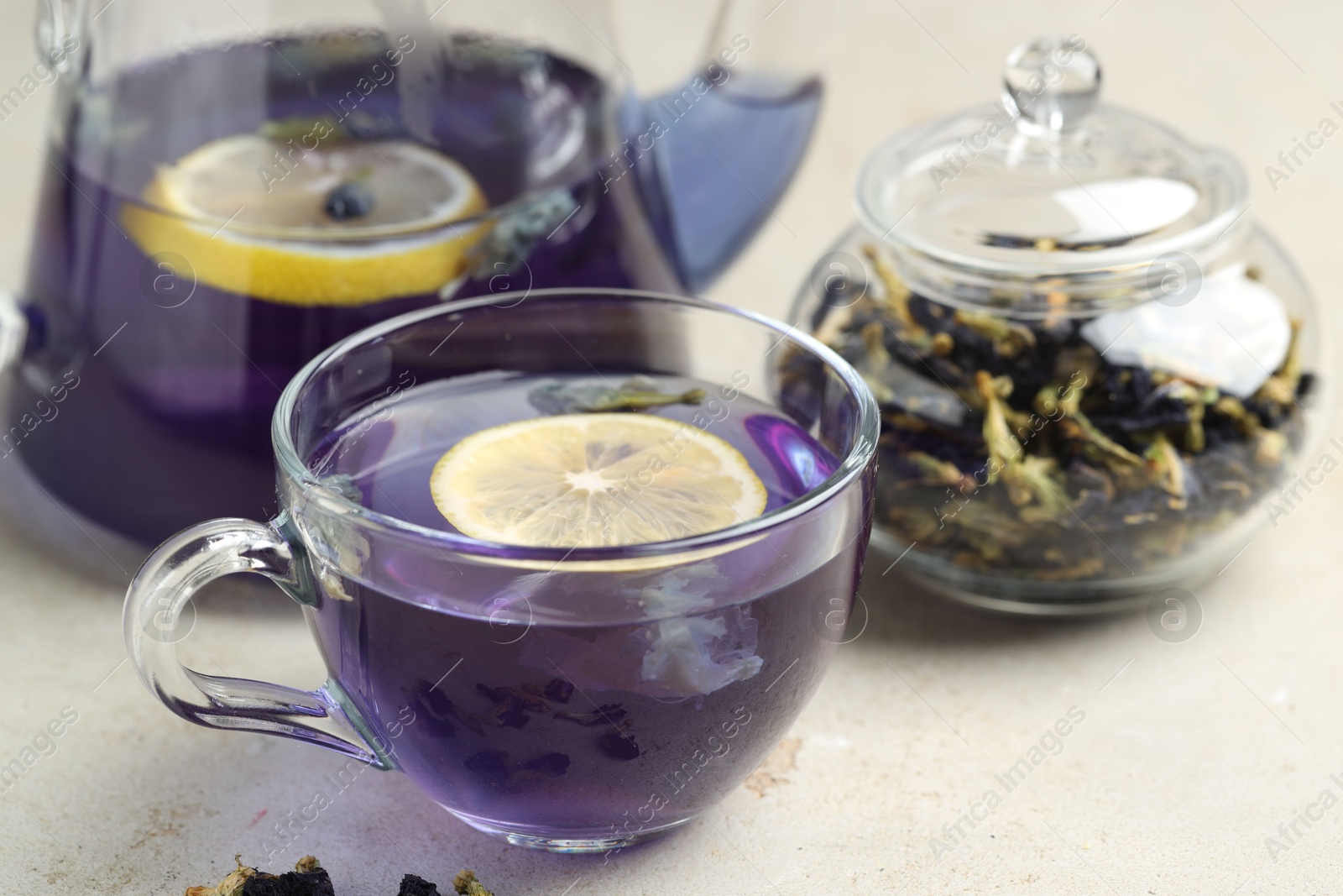 Photo of Delicious butterfly pea flower tea with lemon on gray textured table, closeup