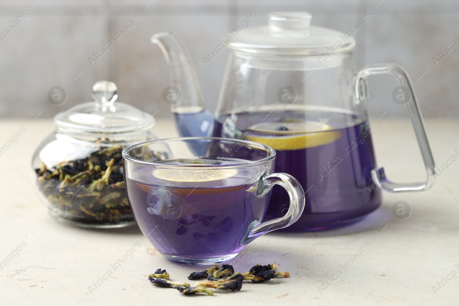 Photo of Delicious butterfly pea flower tea with lemon on gray textured table