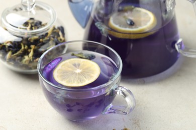 Photo of Delicious butterfly pea flower tea with lemon on gray textured table, closeup