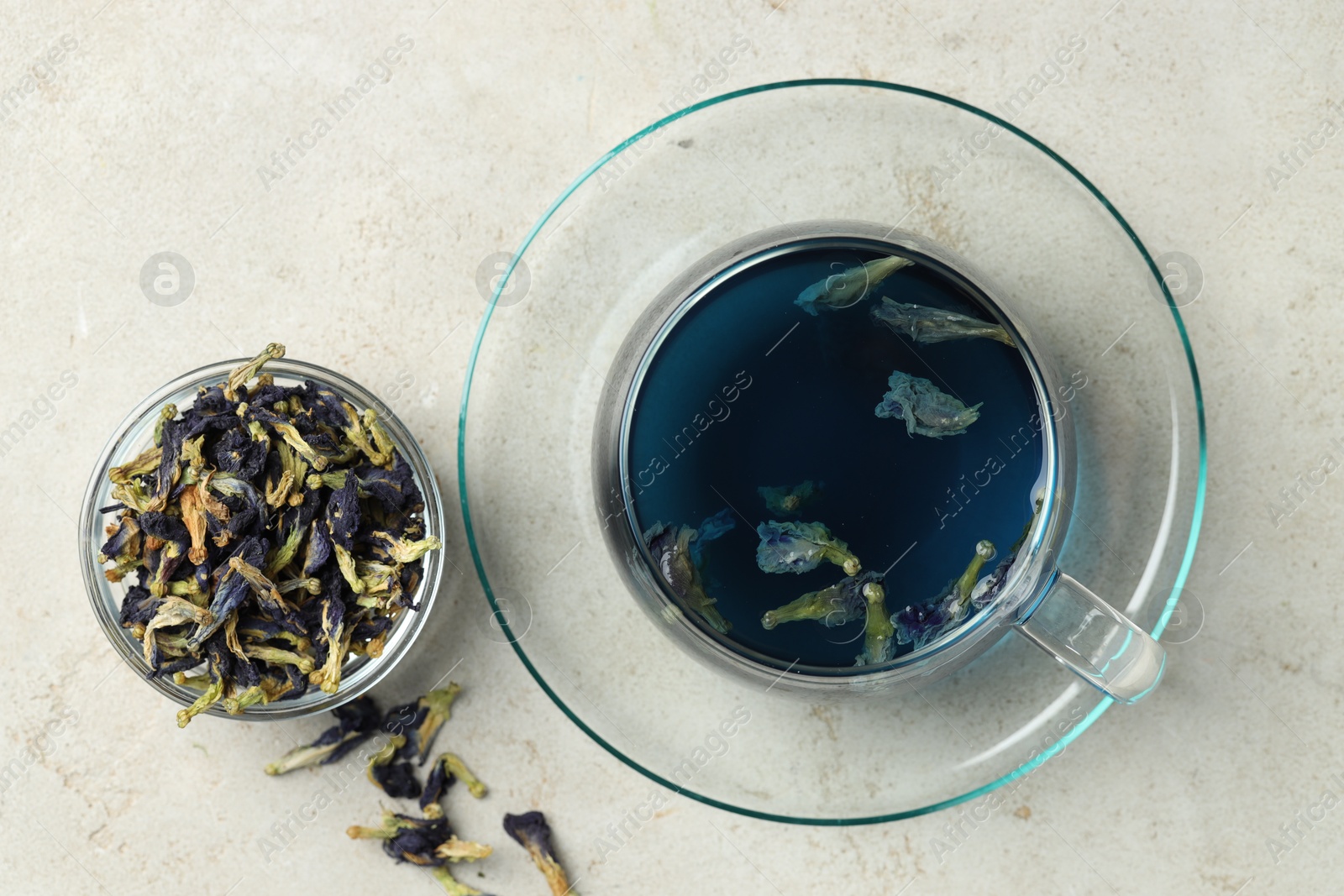 Photo of Delicious butterfly pea flower tea on gray textured table, flat lay