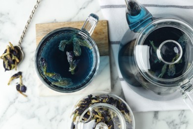 Photo of Delicious butterfly pea flower tea on white marble table, flat lay