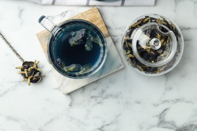 Photo of Delicious butterfly pea flower tea on white marble table, flat lay. Space for text