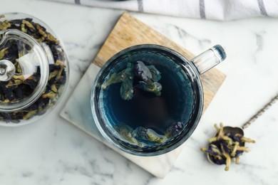 Photo of Delicious butterfly pea flower tea on white marble table, flat lay