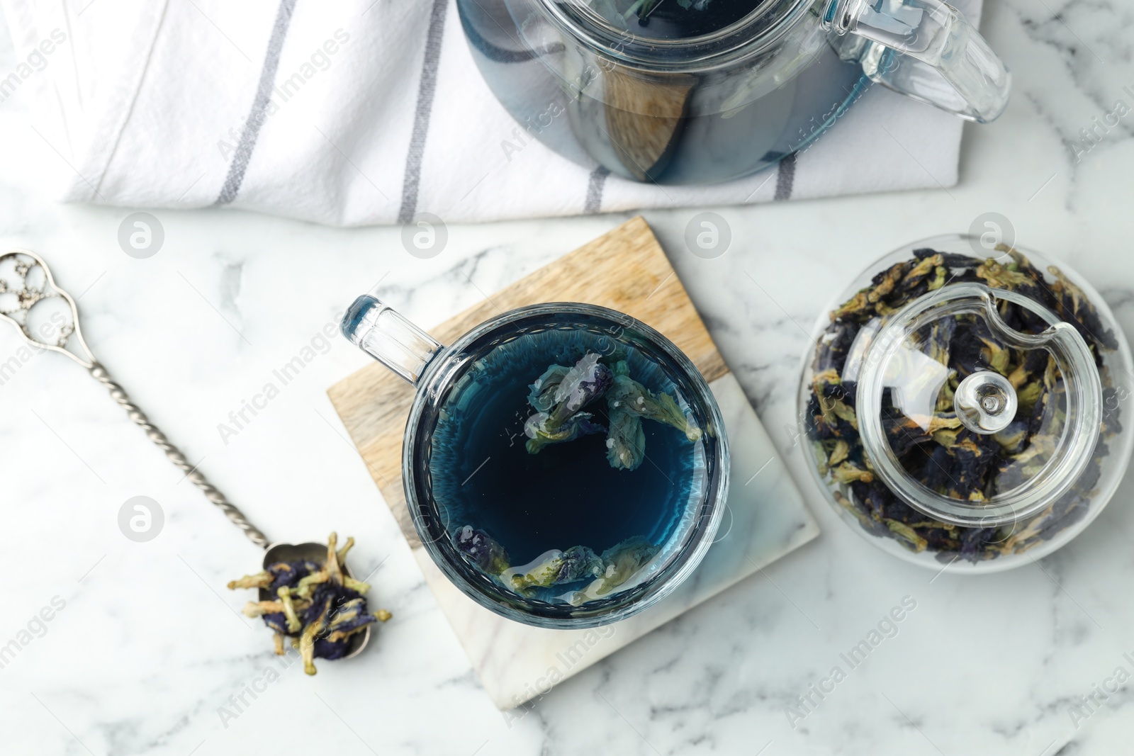 Photo of Delicious butterfly pea flower tea on white marble table, flat lay