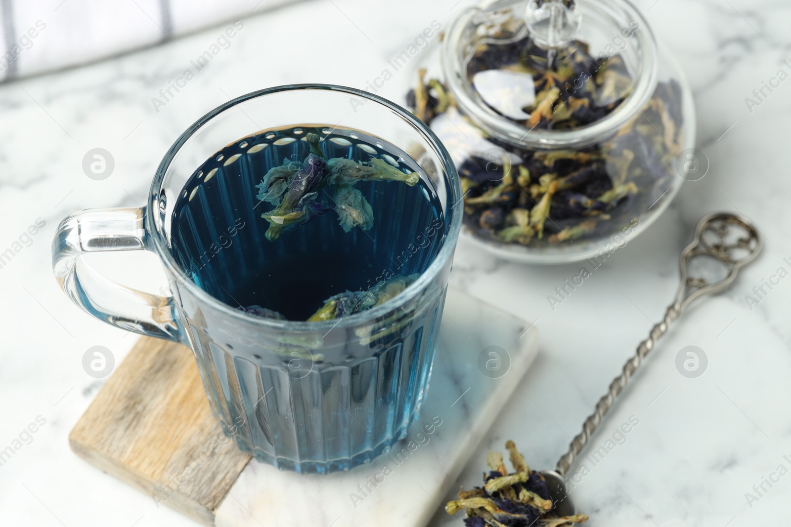 Photo of Delicious butterfly pea flower tea on white marble table, closeup