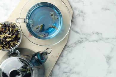 Photo of Delicious butterfly pea flower tea on white marble table, top view. Space for text