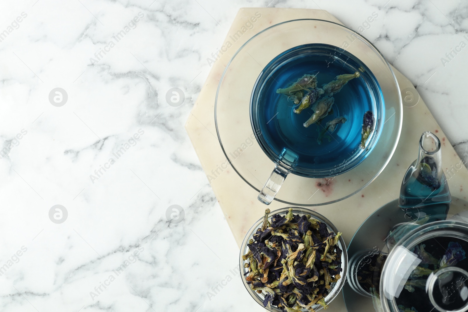 Photo of Delicious butterfly pea flower tea on white marble table, top view. Space for text