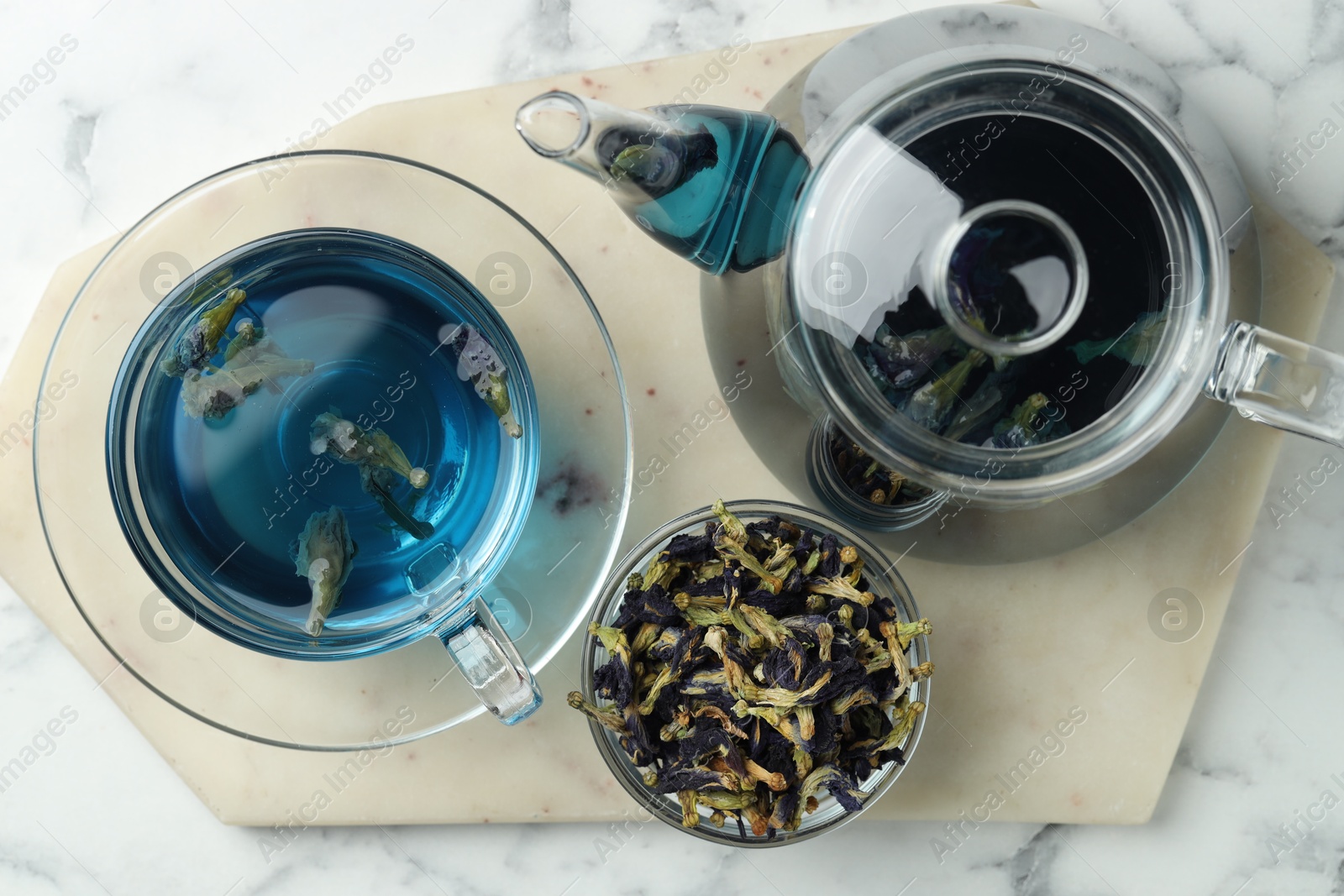 Photo of Delicious butterfly pea flower tea on white marble table, top view