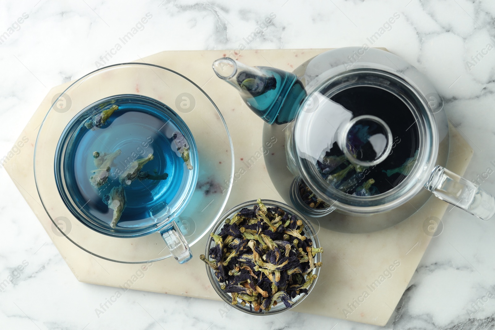 Photo of Delicious butterfly pea flower tea on white marble table, top view