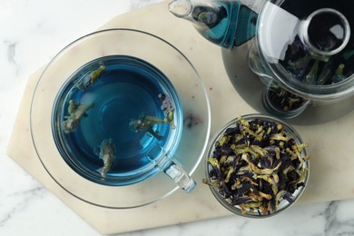 Photo of Delicious butterfly pea flower tea on white marble table, top view