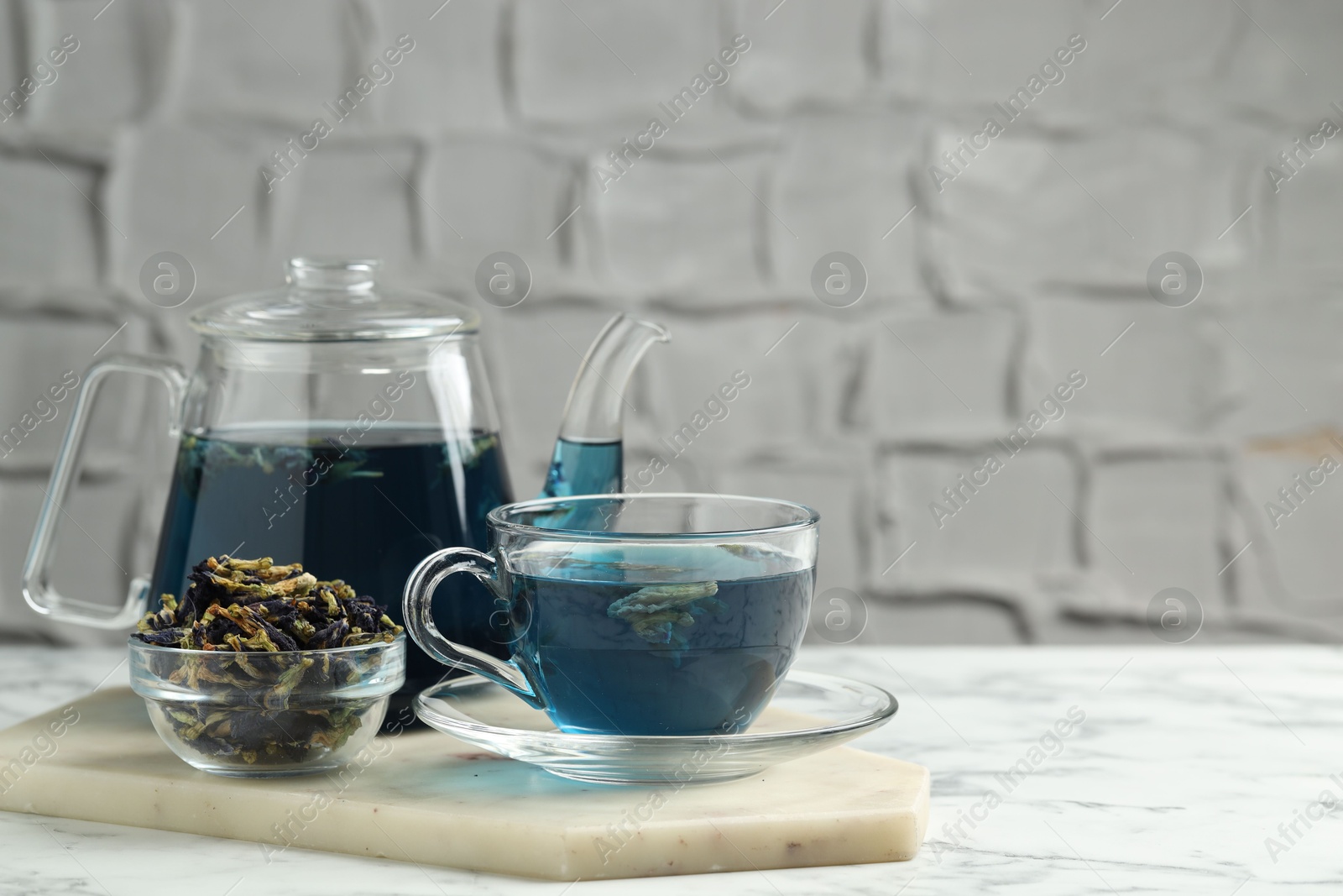 Photo of Delicious butterfly pea flower tea on white marble table against light background, space for text