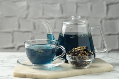 Photo of Delicious butterfly pea flower tea on white marble table against light background