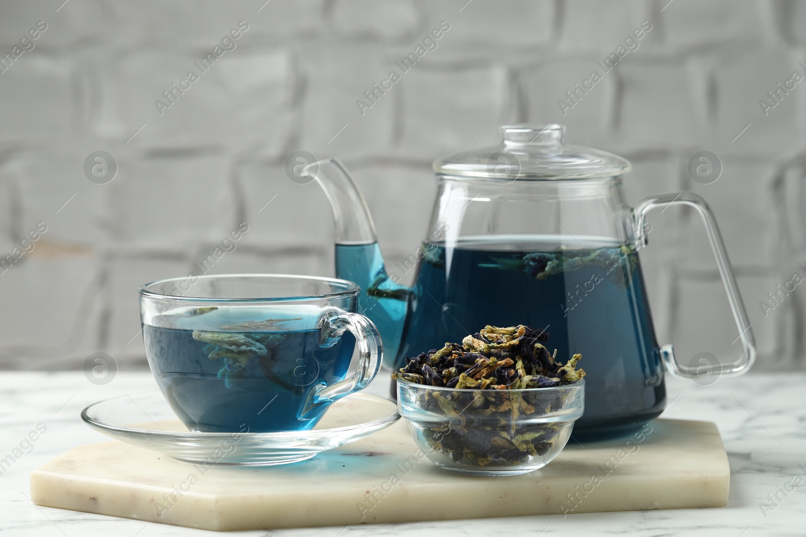 Photo of Delicious butterfly pea flower tea on white marble table against light background