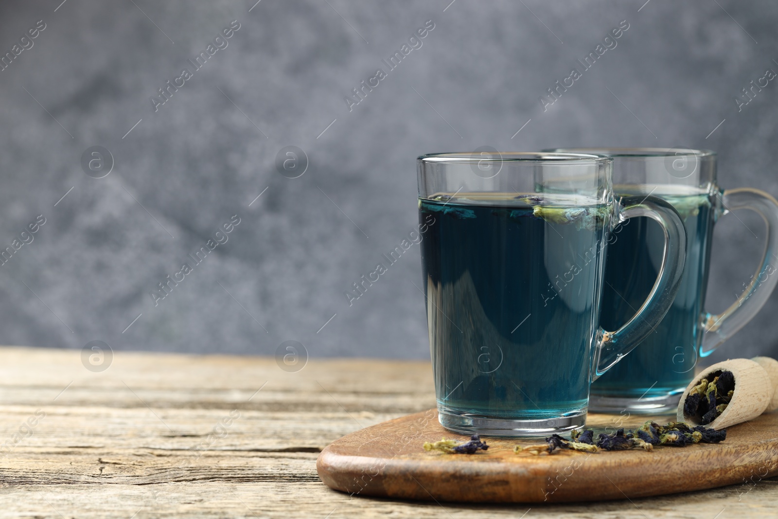 Photo of Delicious butterfly pea flower tea on wooden table against gray background, space for text