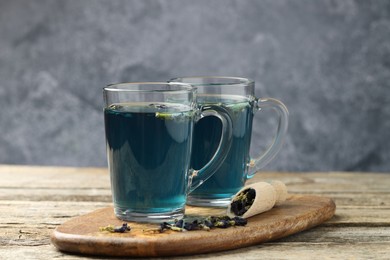 Photo of Delicious butterfly pea flower tea on wooden table against gray background