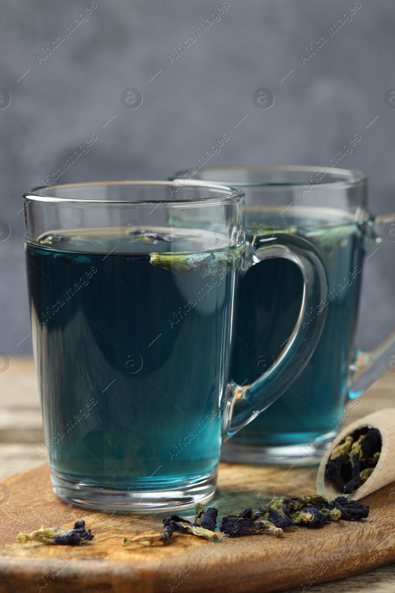 Photo of Delicious butterfly pea flower tea on wooden table against gray background