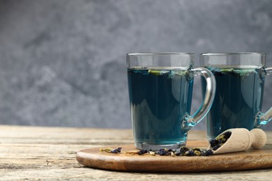 Photo of Delicious butterfly pea flower tea on wooden table against gray background, space for text