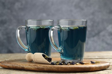 Photo of Delicious butterfly pea flower tea on wooden table against gray background