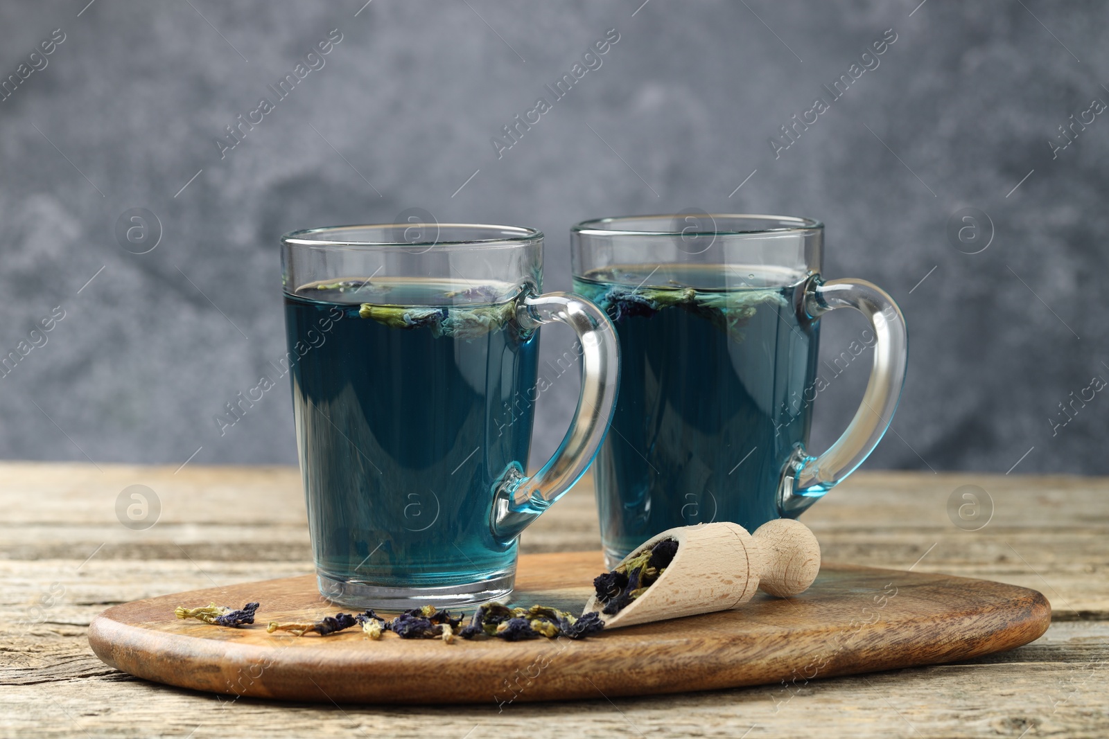 Photo of Delicious butterfly pea flower tea on wooden table against gray background