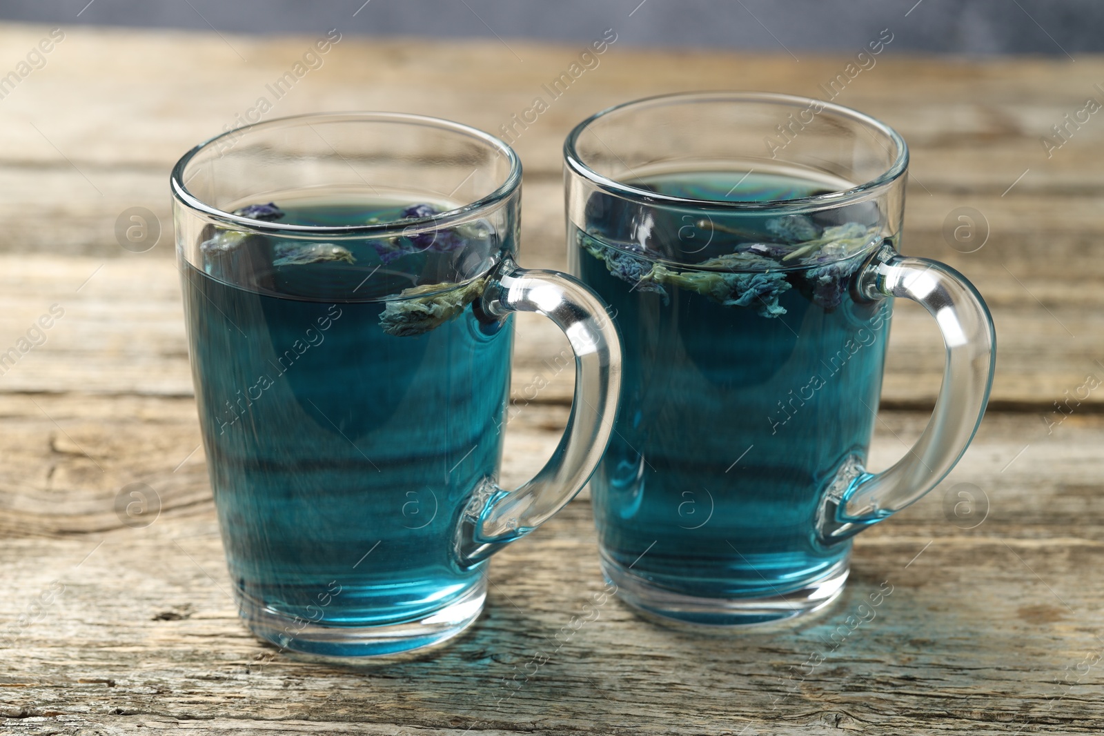 Photo of Delicious butterfly pea flower tea in cups on wooden table