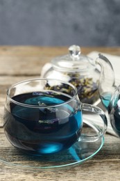 Photo of Delicious butterfly pea flower tea on wooden table against gray background