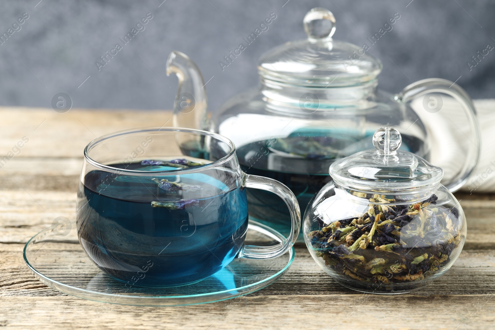 Photo of Delicious butterfly pea flower tea on wooden table against gray background