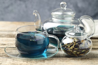 Photo of Delicious butterfly pea flower tea on wooden table against gray background