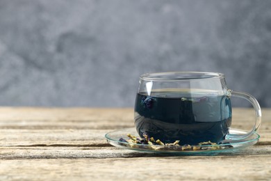 Photo of Delicious butterfly pea flower tea on wooden table against gray background, space for text