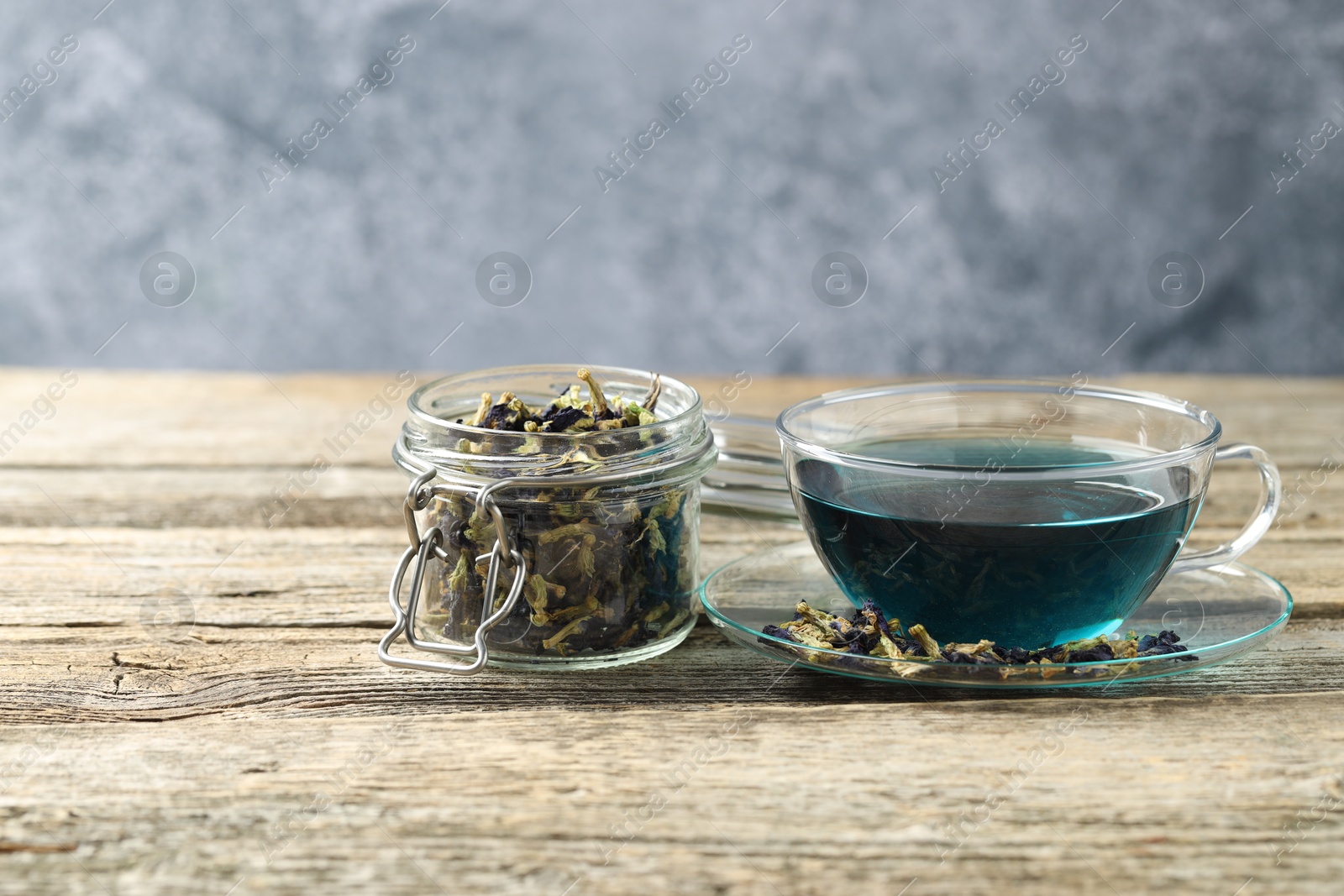 Photo of Delicious butterfly pea flower tea on wooden table against gray background, space for text