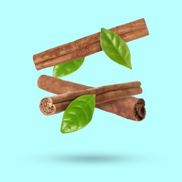 Image of Cinnamon sticks and green leaves in air on light blue background