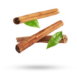 Cinnamon sticks and green leaves in air on white background