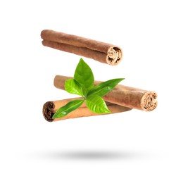 Image of Cinnamon sticks and green leaves in air on white background