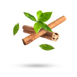 Image of Cinnamon sticks and green leaves in air on white background