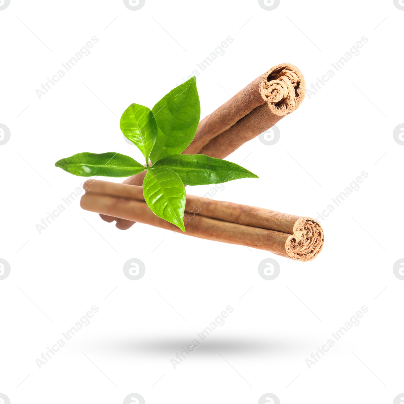 Image of Cinnamon sticks and green leaves in air on white background