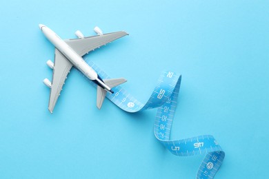 Photo of Plane model takes off and measuring tape as condensation trail on light blue background, top view