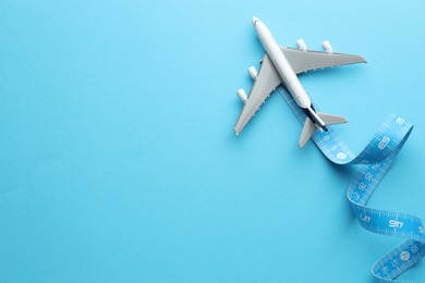 Photo of Plane model takes off and measuring tape as condensation trail on light blue background, top view. Space for text