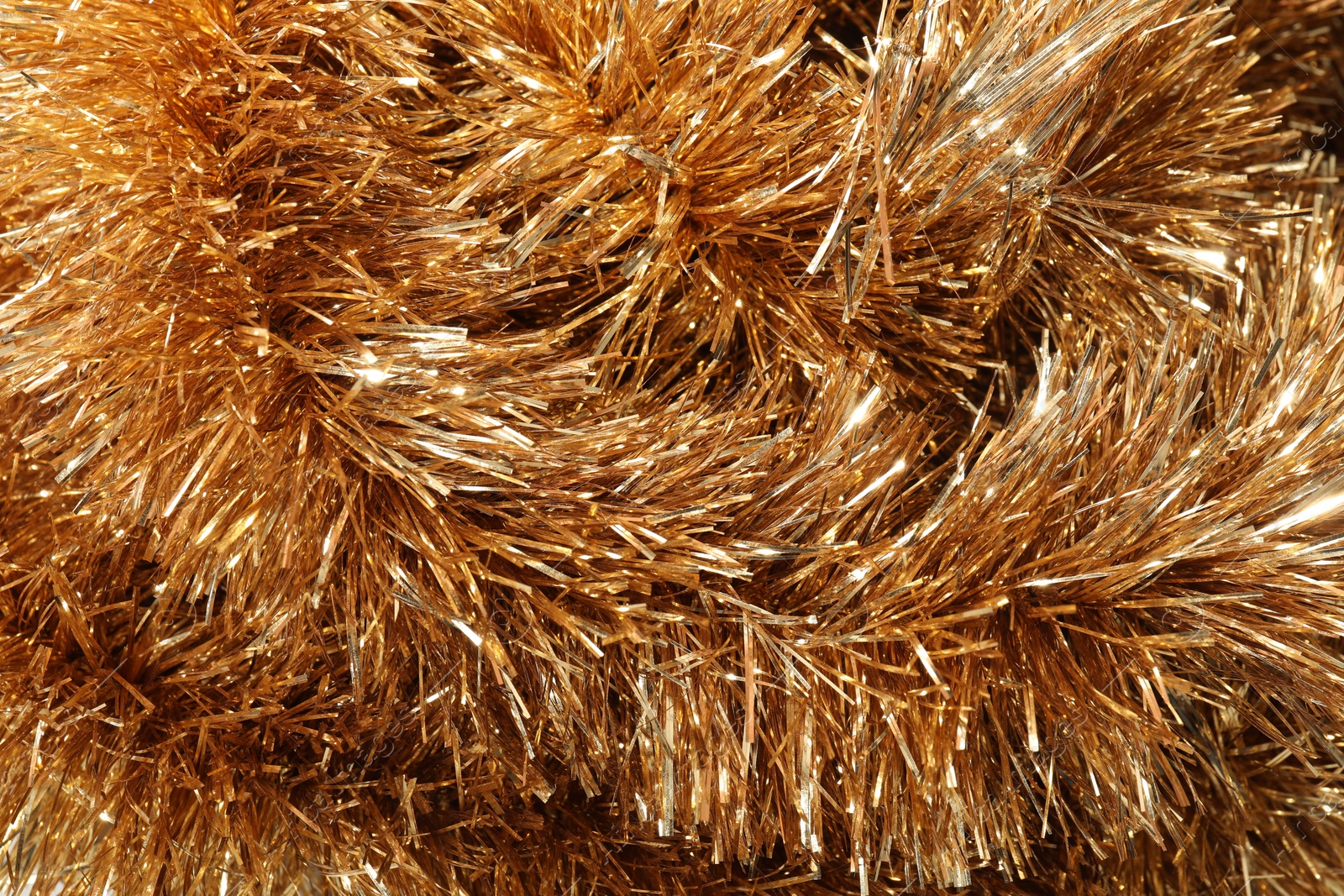 Photo of Shiny golden tinsel as background, closeup view