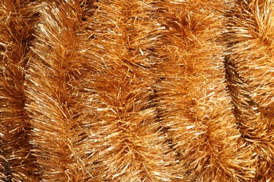 Photo of Shiny golden tinsel as background, closeup view