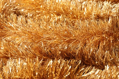 Photo of Shiny golden tinsel as background, closeup view