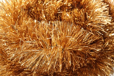 Photo of Shiny golden tinsel as background, closeup view