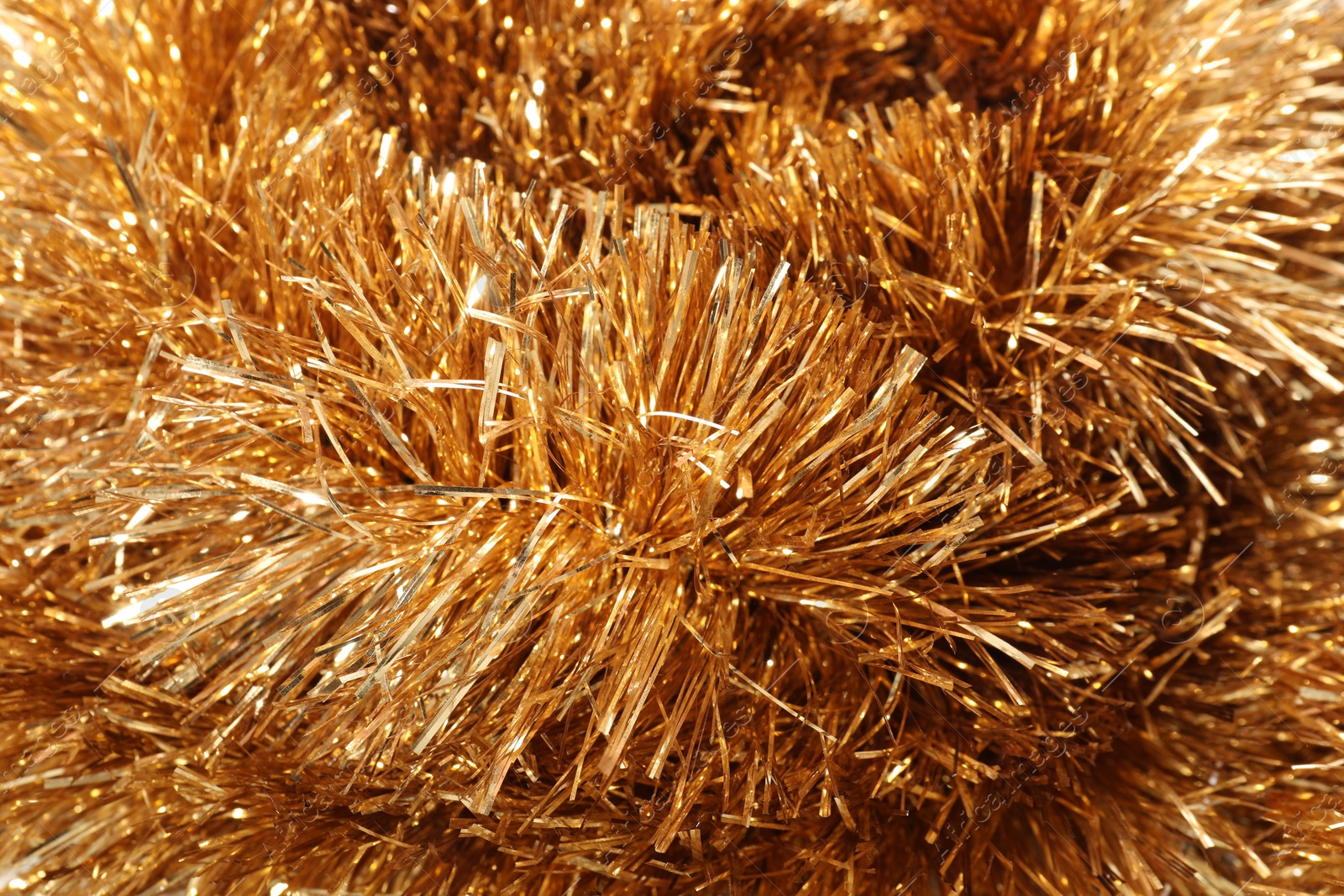 Photo of Shiny golden tinsel as background, closeup view