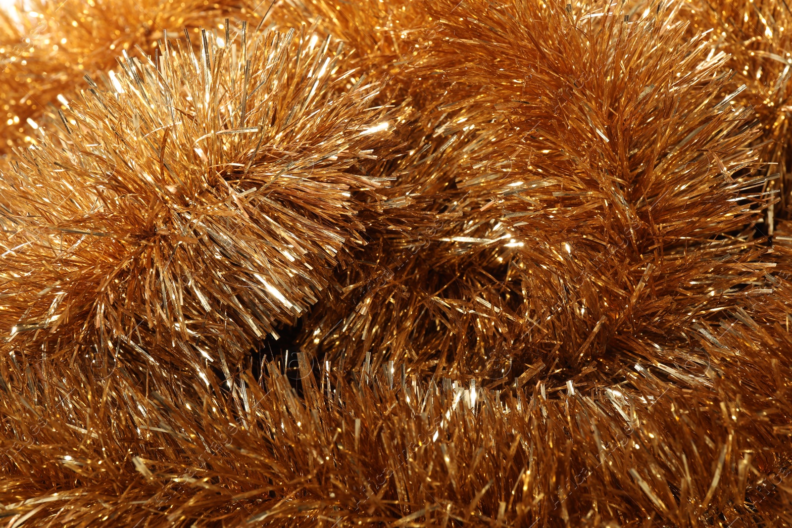 Photo of Shiny golden tinsel as background, closeup view