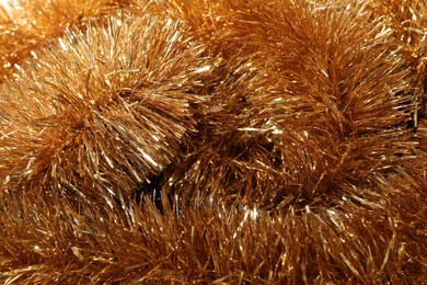 Photo of Shiny golden tinsel as background, closeup view