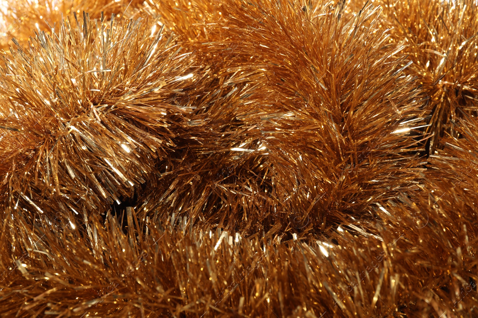 Photo of Shiny golden tinsel as background, closeup view