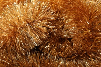 Photo of Shiny golden tinsel as background, closeup view