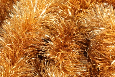 Photo of Shiny golden tinsel as background, closeup view