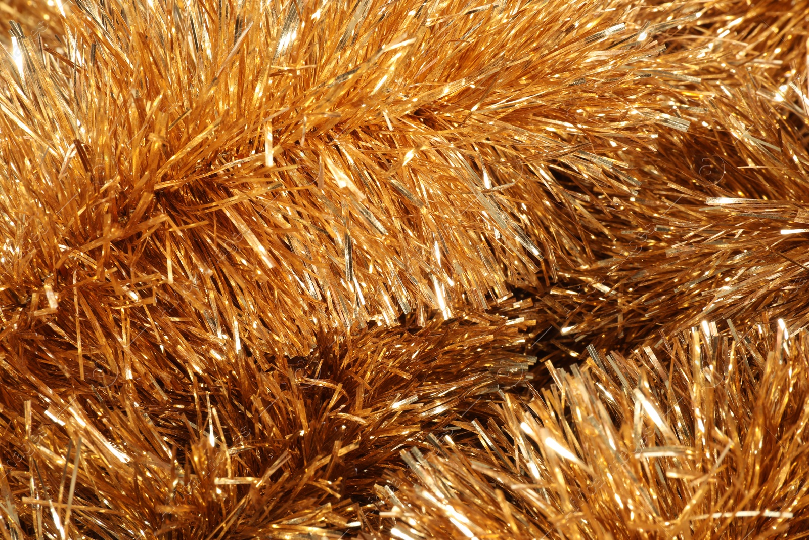 Photo of Shiny golden tinsel as background, closeup view