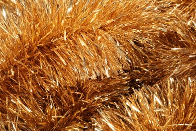 Photo of Shiny golden tinsel as background, closeup view